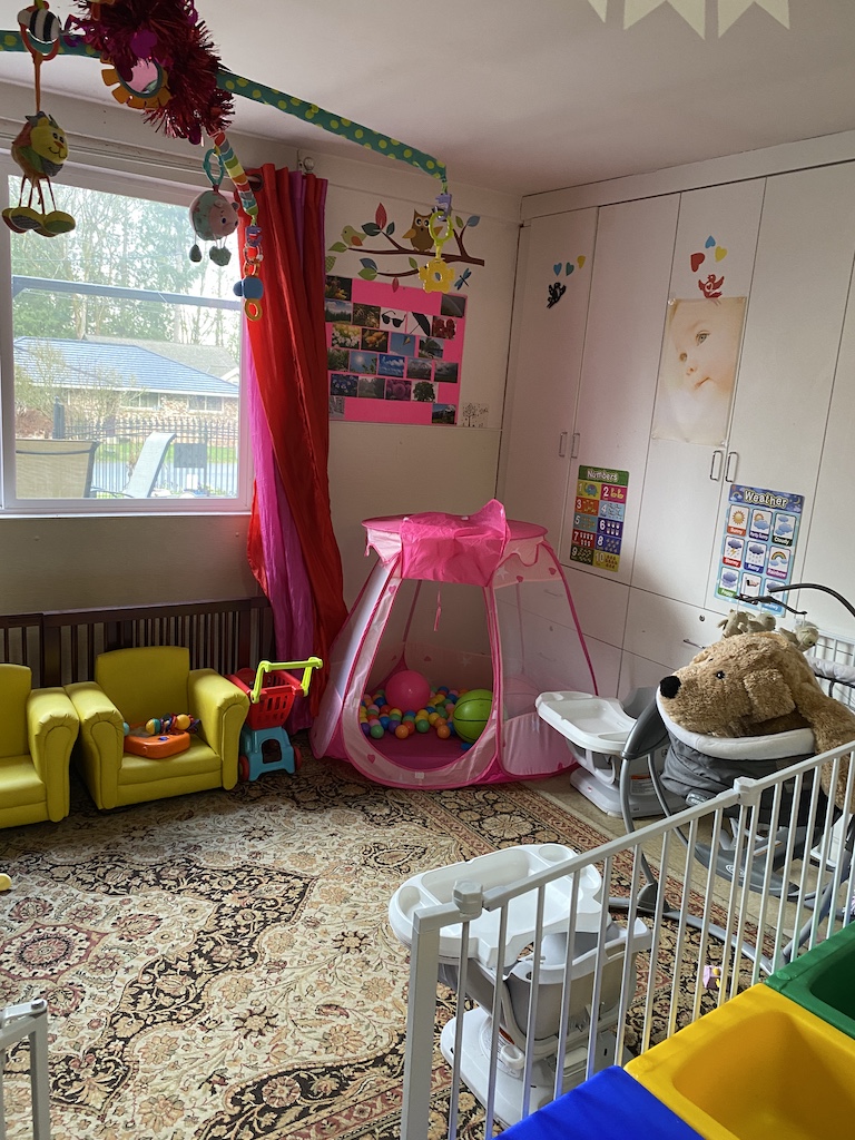 A cozy nursery featuring a crib, a playpen, and a teddy bear, creating a warm and inviting atmosphere for a child.