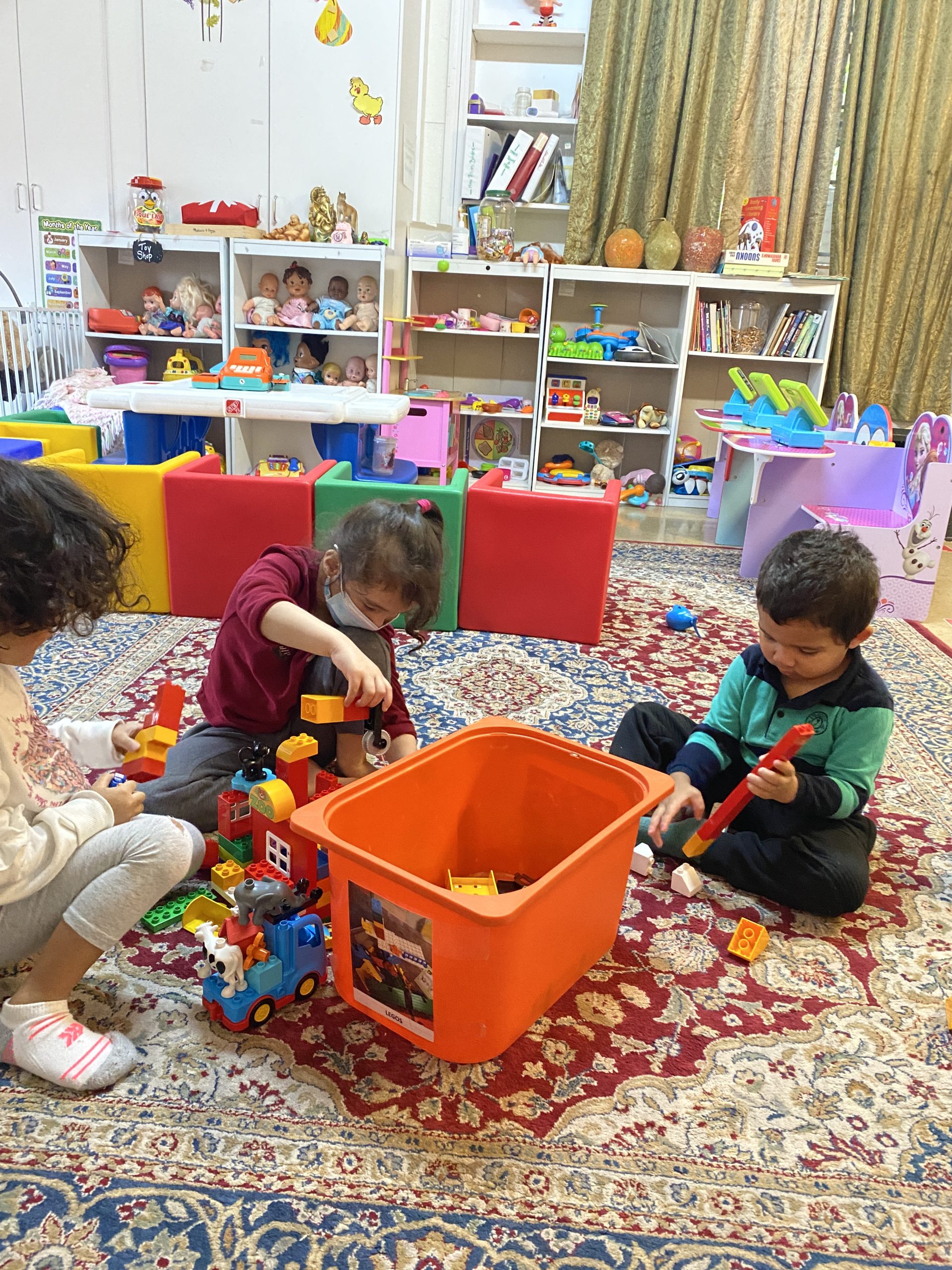 Children joyfully building with colorful blocks in a bright, spacious room filled with natural light.