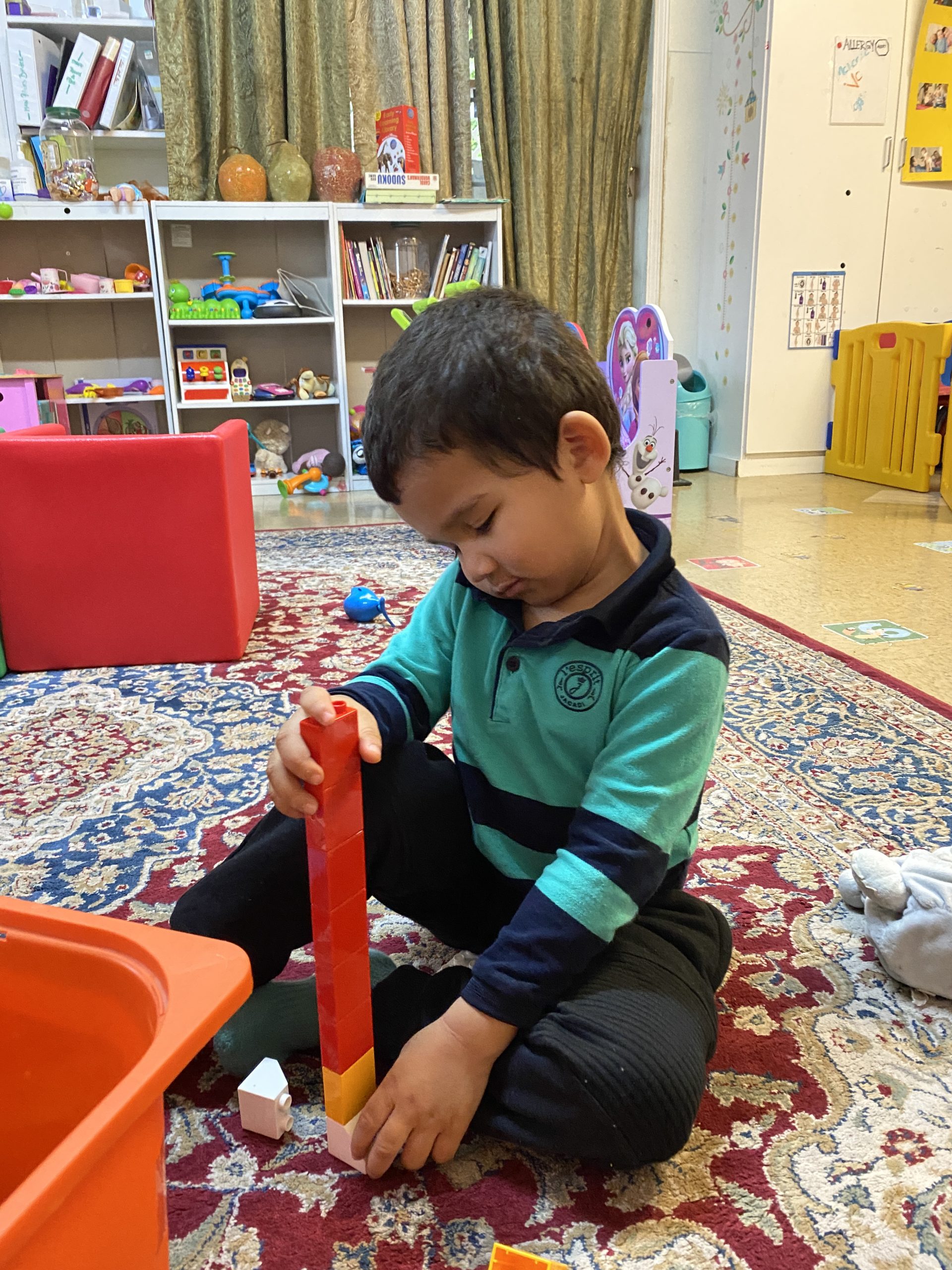 A young boy joyfully playing with a colorful toy in a bright, cheerful room.